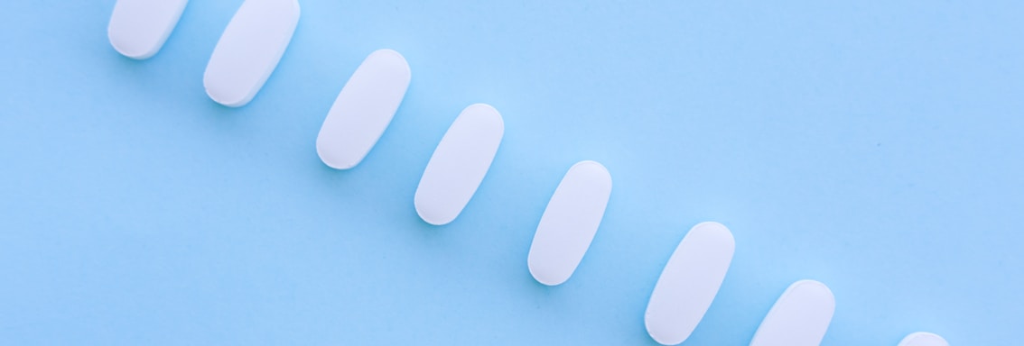 A row of white pills sitting on top of a blue surface